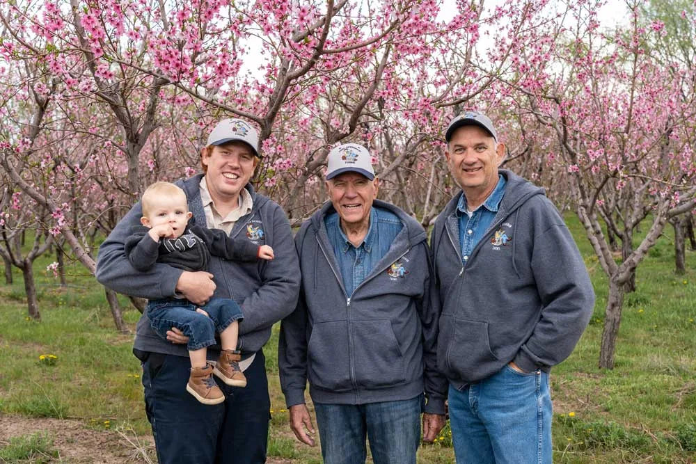 Four generations of Fred in peach orchard in bloom in Santaquin, Utah